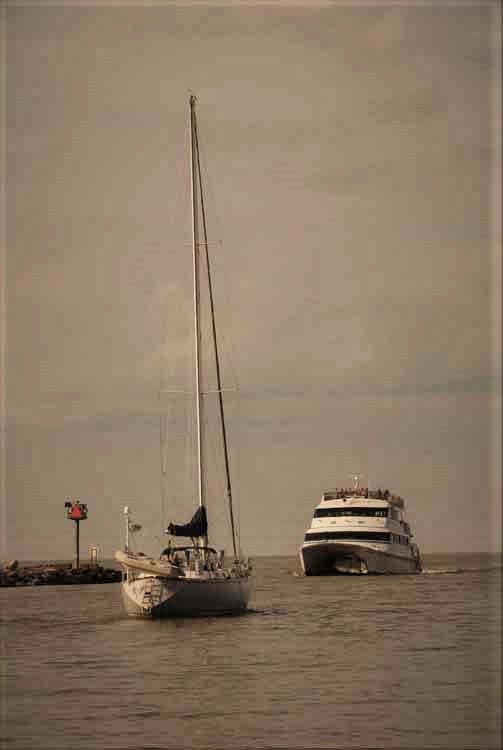 sailboat and jet express pass in water